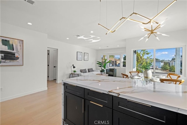 kitchen with light hardwood / wood-style floors, light stone countertops, and a chandelier