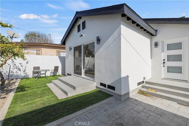 rear view of property featuring a patio area and a lawn