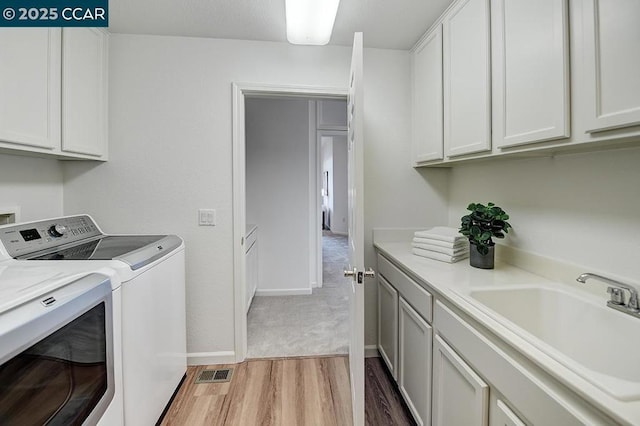 washroom with sink, cabinets, washing machine and dryer, and wood-type flooring