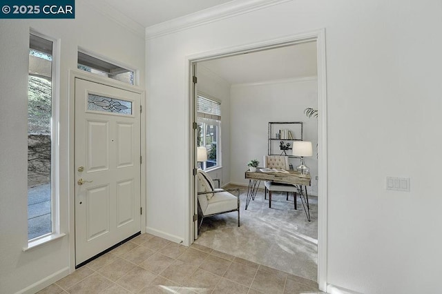 carpeted foyer entrance featuring crown molding and a healthy amount of sunlight