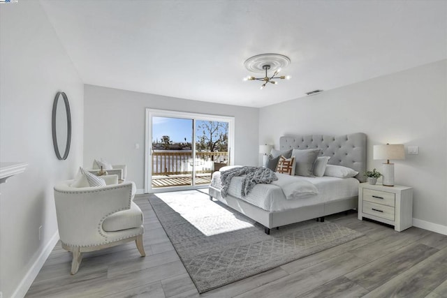 bedroom featuring light hardwood / wood-style flooring, access to outside, and an inviting chandelier