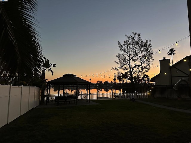 yard at dusk with a water view and a gazebo