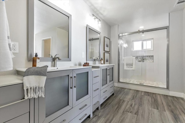 bathroom with hardwood / wood-style floors, walk in shower, and vanity