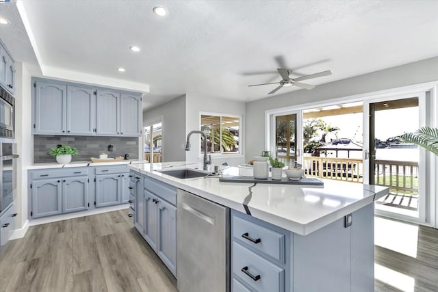 kitchen featuring sink, ceiling fan, decorative backsplash, a center island with sink, and appliances with stainless steel finishes