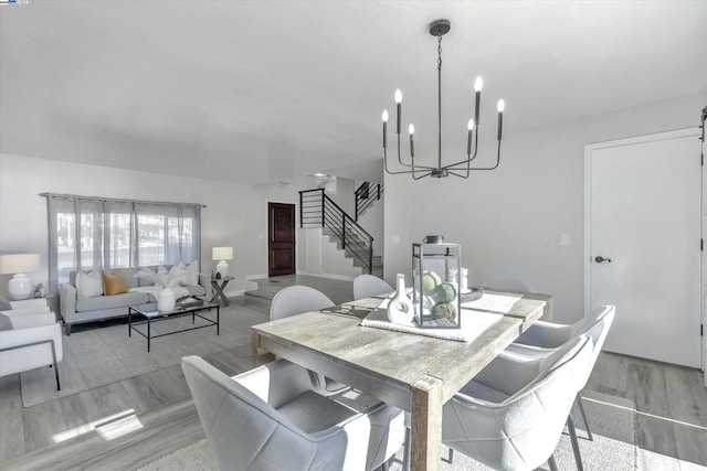 dining area with light hardwood / wood-style floors and an inviting chandelier