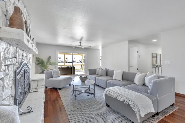 living room with hardwood / wood-style flooring, ceiling fan, and a fireplace