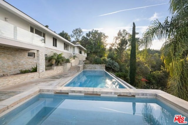 view of swimming pool with an in ground hot tub