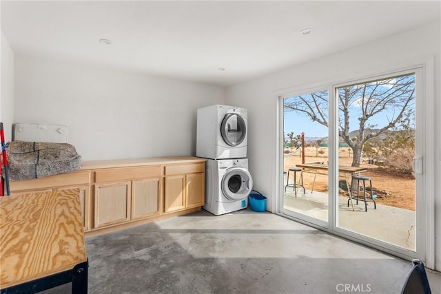 washroom featuring stacked washer / dryer and cabinet space