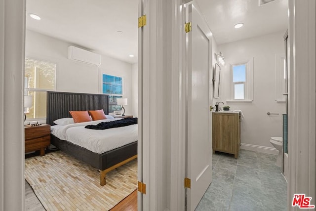 bedroom with ensuite bathroom and an AC wall unit