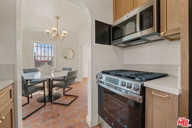 kitchen with light tile patterned flooring, pendant lighting, appliances with stainless steel finishes, and an inviting chandelier