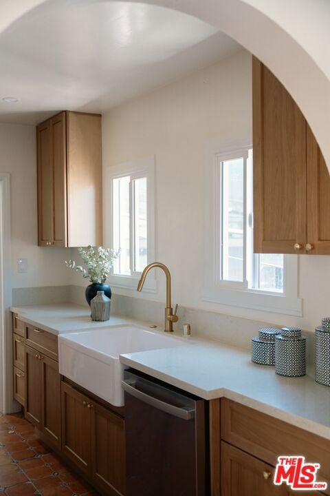 kitchen with dishwasher, sink, and dark tile patterned flooring