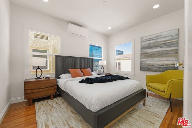 bedroom with hardwood / wood-style flooring and a wall unit AC