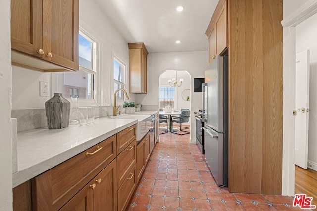 kitchen with light stone countertops, tile patterned flooring, stainless steel fridge, and sink