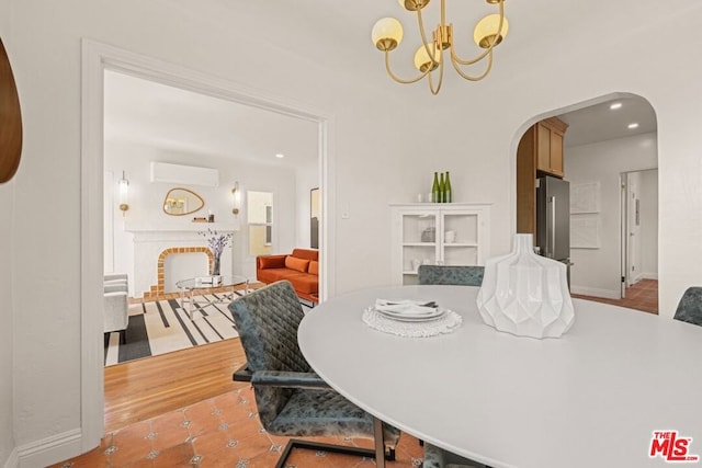 tiled dining area featuring a wall mounted air conditioner and a notable chandelier