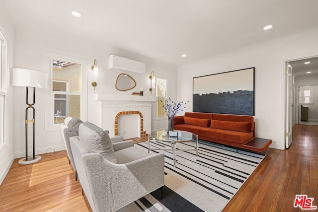 living room with a brick fireplace, light wood-type flooring, and a wall mounted air conditioner