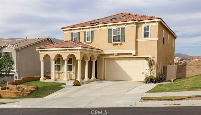 mediterranean / spanish house featuring a garage, covered porch, and solar panels