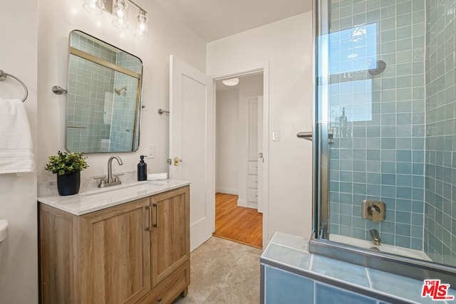 bathroom featuring a shower with door, vanity, and tile patterned flooring