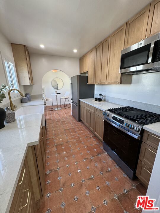 kitchen featuring sink, dark tile patterned flooring, and stainless steel appliances