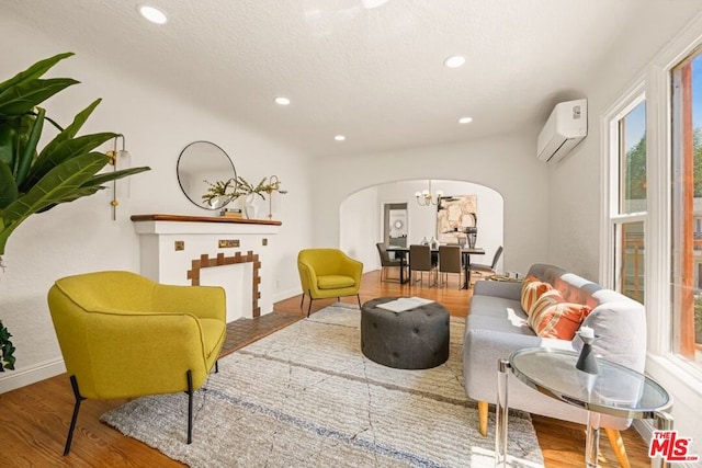 living area featuring a chandelier, hardwood / wood-style floors, and a wall mounted AC