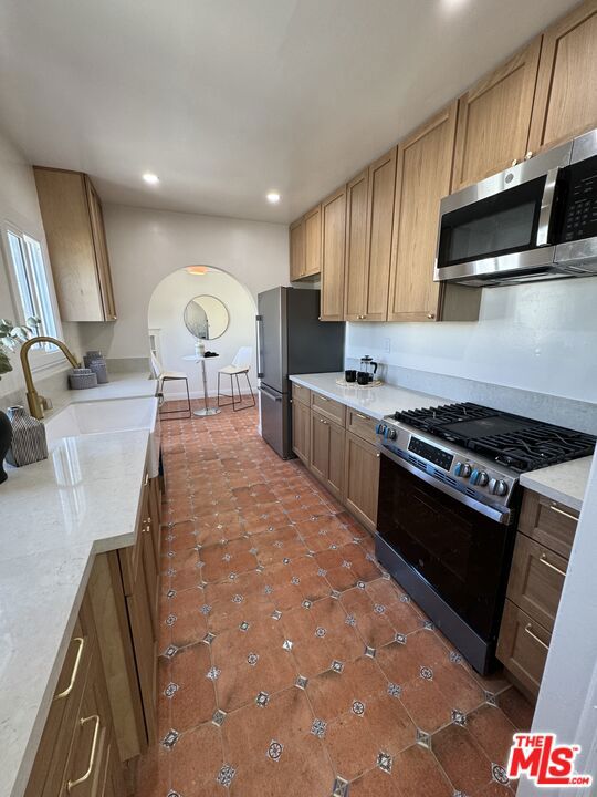 kitchen with dark tile patterned floors, sink, and stainless steel appliances