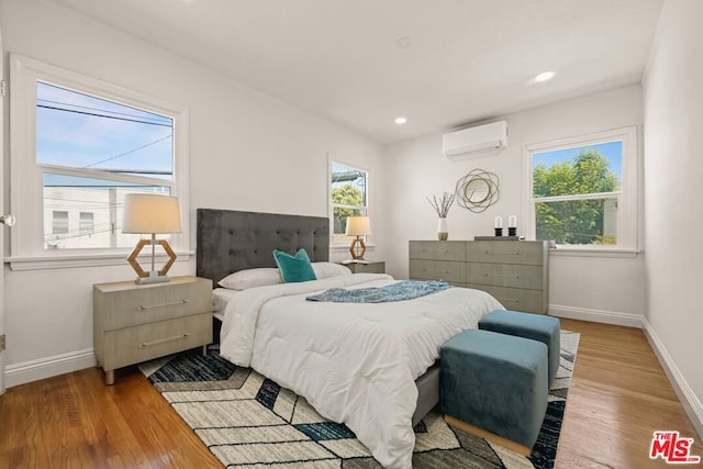 bedroom featuring light hardwood / wood-style floors and a wall unit AC