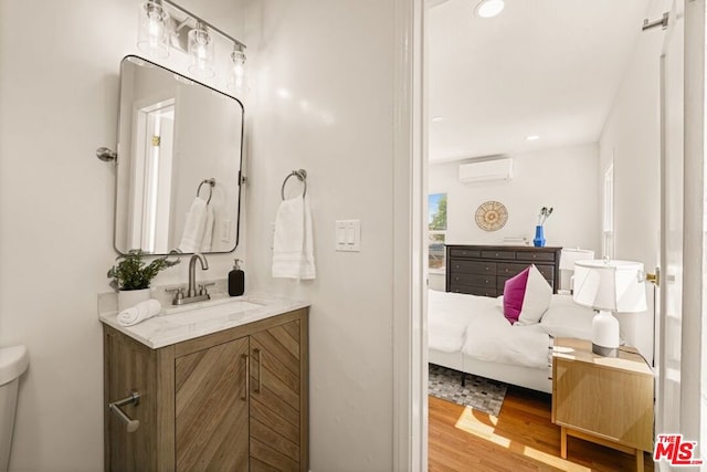 bathroom with toilet, a wall mounted AC, hardwood / wood-style flooring, and vanity