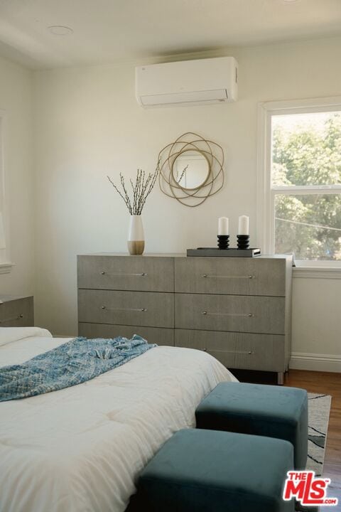 bedroom with dark hardwood / wood-style flooring and a wall unit AC