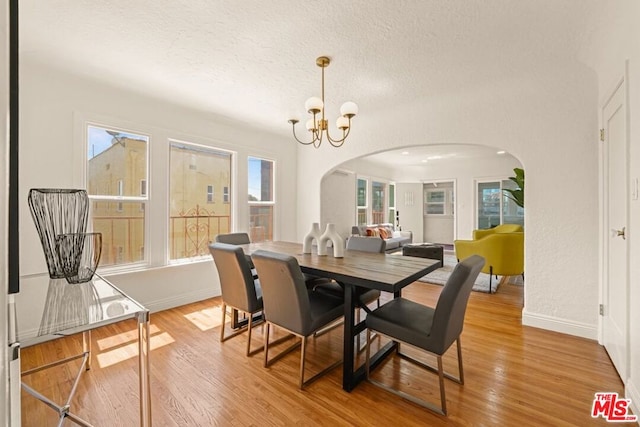 dining room with a textured ceiling, an inviting chandelier, and light hardwood / wood-style flooring