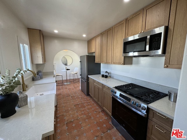 kitchen featuring appliances with stainless steel finishes, dark tile patterned floors, and sink