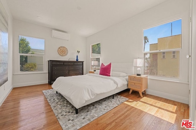 bedroom with wood-type flooring and a wall unit AC