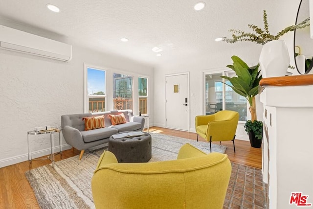 living room featuring a wall mounted AC, a textured ceiling, and wood-type flooring