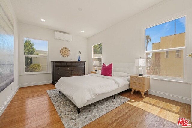 bedroom with light wood-type flooring and a wall mounted air conditioner