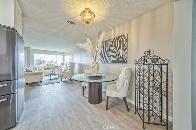 dining area with a textured ceiling and light hardwood / wood-style floors