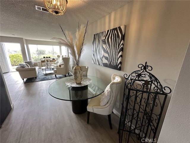 dining area with a chandelier, a textured ceiling, and hardwood / wood-style floors