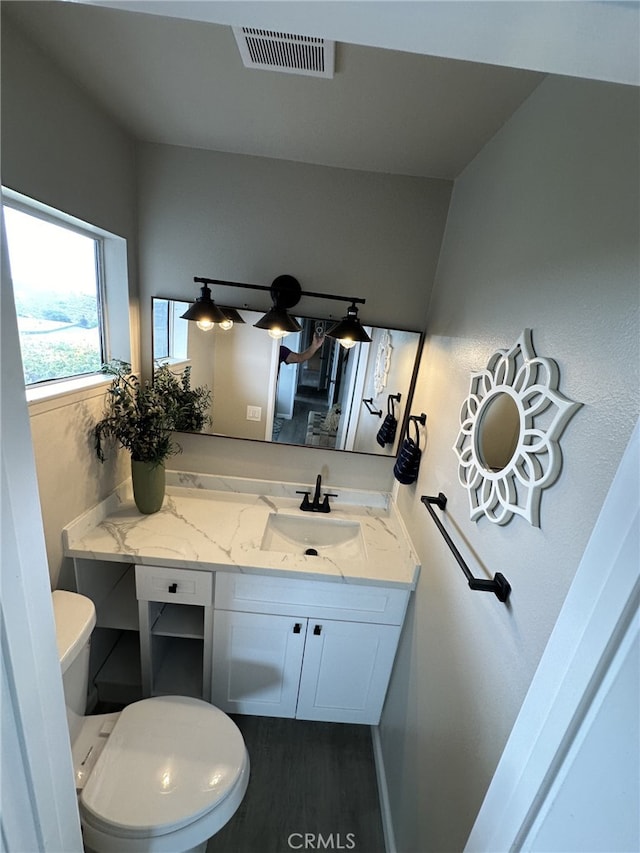 bathroom with toilet, hardwood / wood-style flooring, and vanity