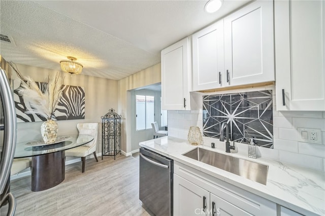 kitchen with light hardwood / wood-style floors, appliances with stainless steel finishes, tasteful backsplash, white cabinets, and sink