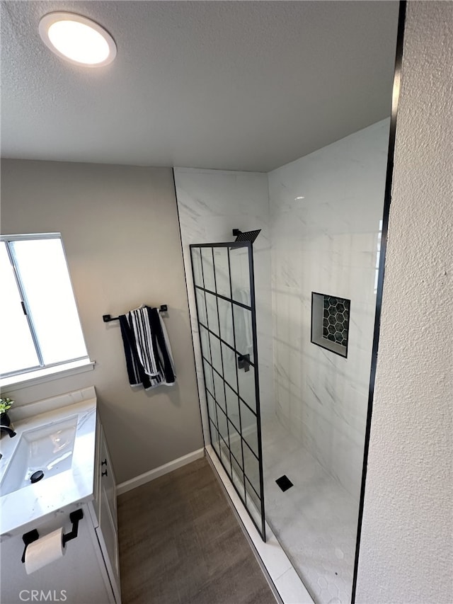 bathroom featuring vanity, tiled shower, and a textured ceiling