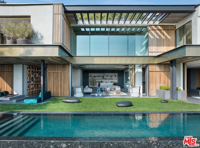 back of house with a lawn, an outdoor living space, and a patio