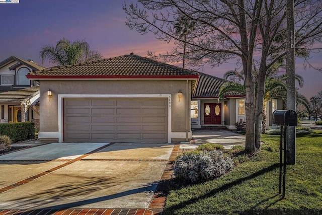 mediterranean / spanish house with a lawn and a garage