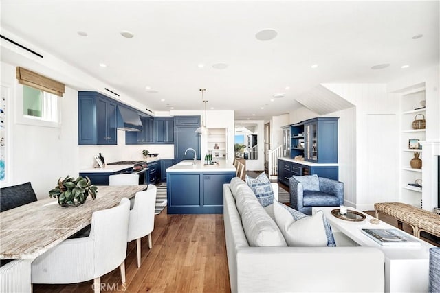 living room with built in features, sink, and light hardwood / wood-style flooring