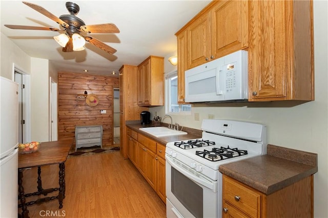 kitchen featuring ceiling fan, wood walls, sink, white appliances, and light wood-type flooring