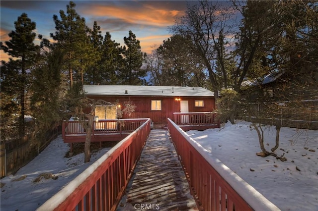 snow covered back of property featuring a wooden deck