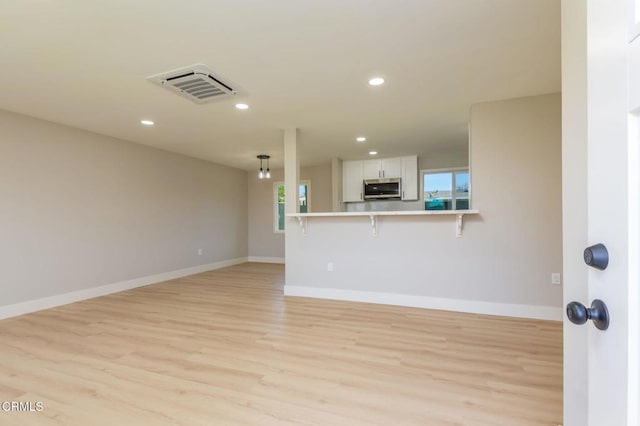 unfurnished living room featuring light wood-type flooring and a wealth of natural light