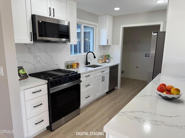 kitchen with stainless steel appliances, tasteful backsplash, light stone countertops, white cabinets, and sink