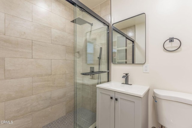 bathroom featuring toilet, an enclosed shower, and vanity