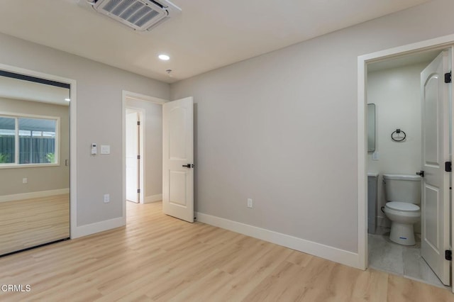 bedroom with light wood-type flooring and connected bathroom