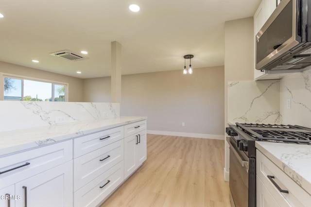 kitchen featuring stainless steel appliances, backsplash, white cabinets, and decorative light fixtures