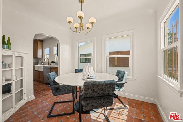 dining area featuring an inviting chandelier, a healthy amount of sunlight, and dark tile patterned floors