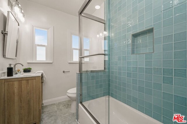 full bathroom featuring toilet, bath / shower combo with glass door, and vanity