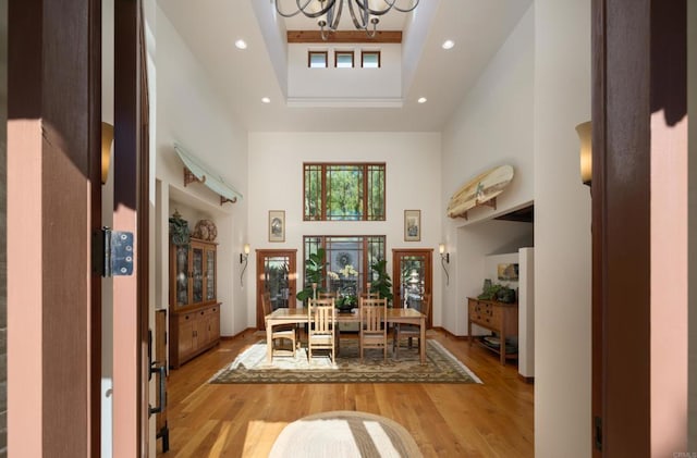 dining space featuring hardwood / wood-style floors, a chandelier, and a high ceiling